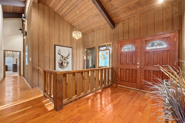 foyer featuring beam ceiling, light wood-type flooring, an inviting chandelier, and wooden ceiling