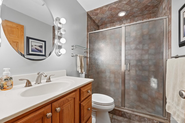 bathroom with vanity, toilet, and a shower with door