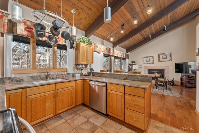 kitchen featuring kitchen peninsula, pendant lighting, stainless steel dishwasher, and a tile fireplace