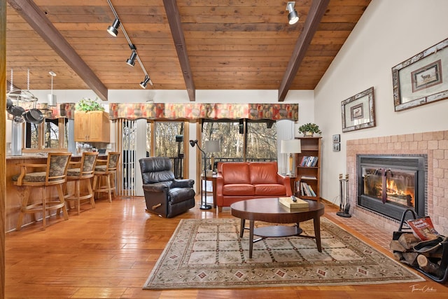 living room with light hardwood / wood-style floors, wooden ceiling, a tile fireplace, and track lighting