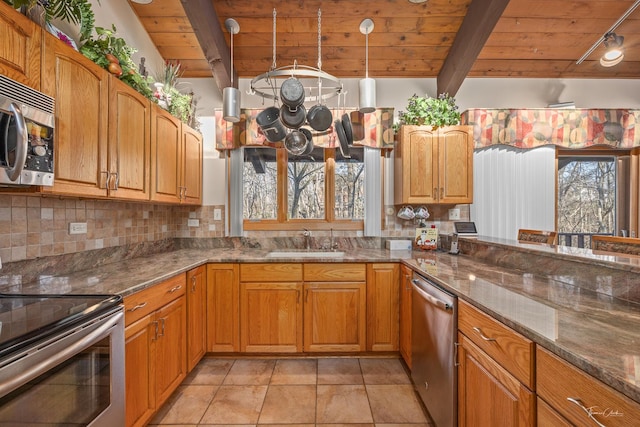 kitchen featuring dark stone counters, sink, beam ceiling, wood ceiling, and stainless steel appliances