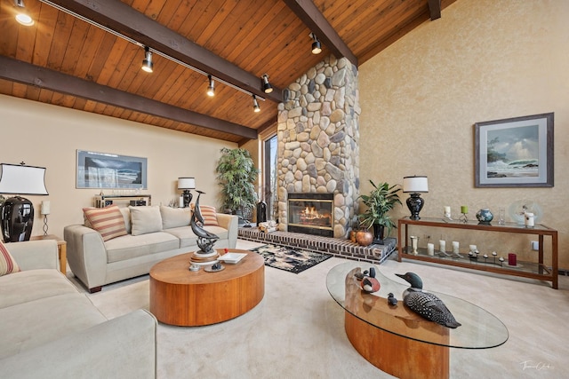 carpeted living room with vaulted ceiling with beams, a stone fireplace, wood ceiling, and track lighting