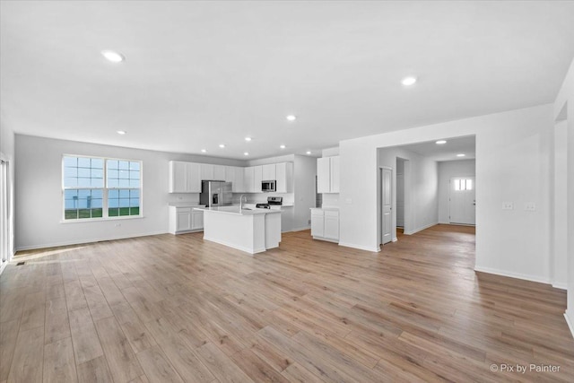 unfurnished living room with light hardwood / wood-style flooring and sink