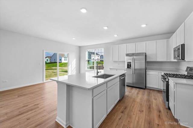 kitchen with a kitchen island with sink, sink, white cabinets, and stainless steel appliances