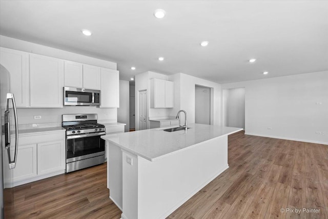 kitchen featuring sink, white cabinetry, stainless steel appliances, and an island with sink