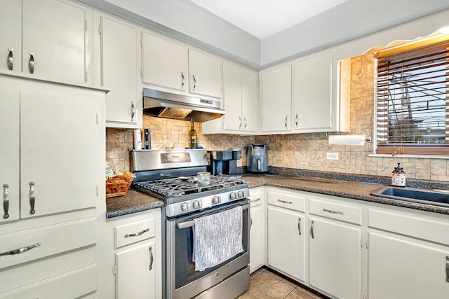 kitchen with stainless steel gas range oven, white cabinets, sink, light tile patterned floors, and tasteful backsplash