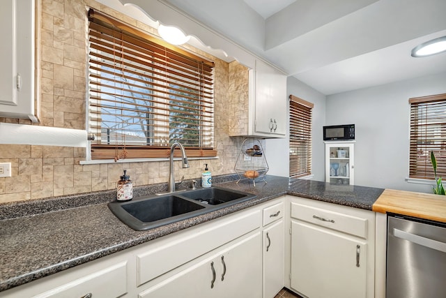 kitchen with backsplash, dishwasher, sink, and white cabinets