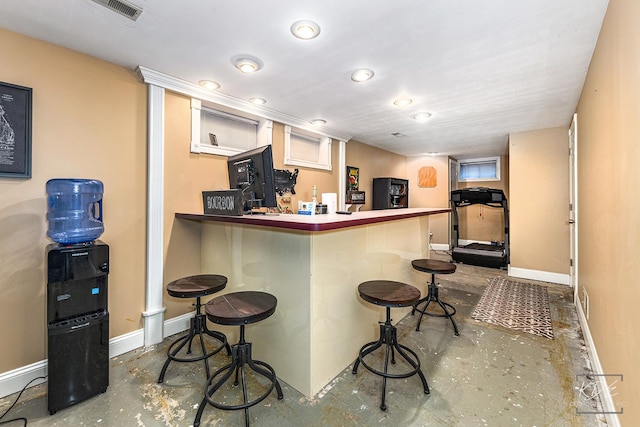 kitchen featuring kitchen peninsula, concrete flooring, and a kitchen breakfast bar