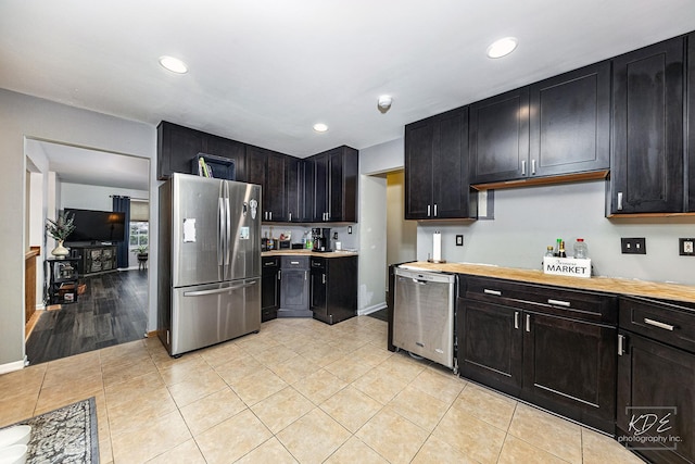 kitchen with stainless steel appliances, wooden counters, and light tile patterned floors