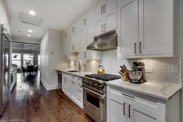 kitchen with dark wood finished floors, appliances with stainless steel finishes, white cabinets, a sink, and under cabinet range hood