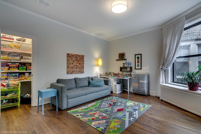 living room featuring radiator heating unit, visible vents, dark wood-type flooring, and ornamental molding