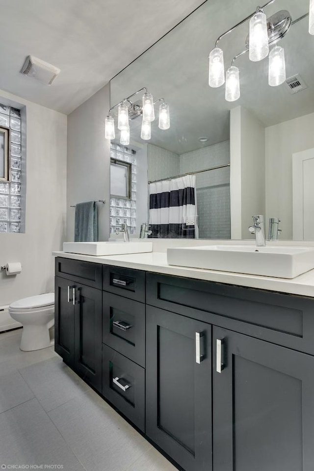 full bath with double vanity, visible vents, toilet, and a sink