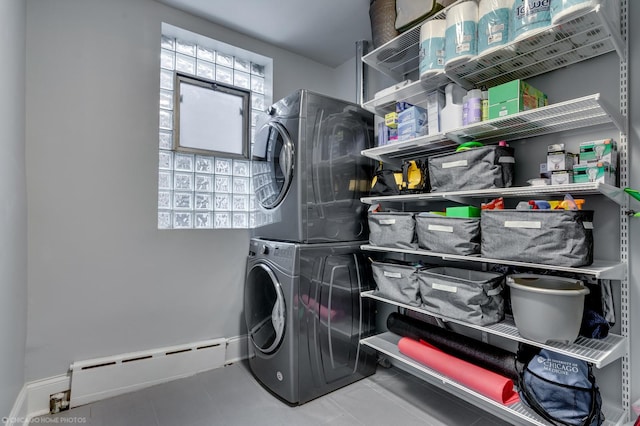 laundry room featuring laundry area, baseboards, baseboard heating, and stacked washer and clothes dryer