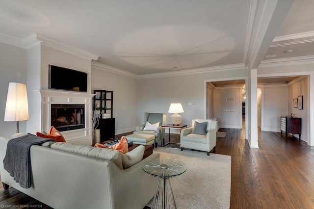 living area with baseboards, ornamental molding, dark wood-style flooring, and a glass covered fireplace