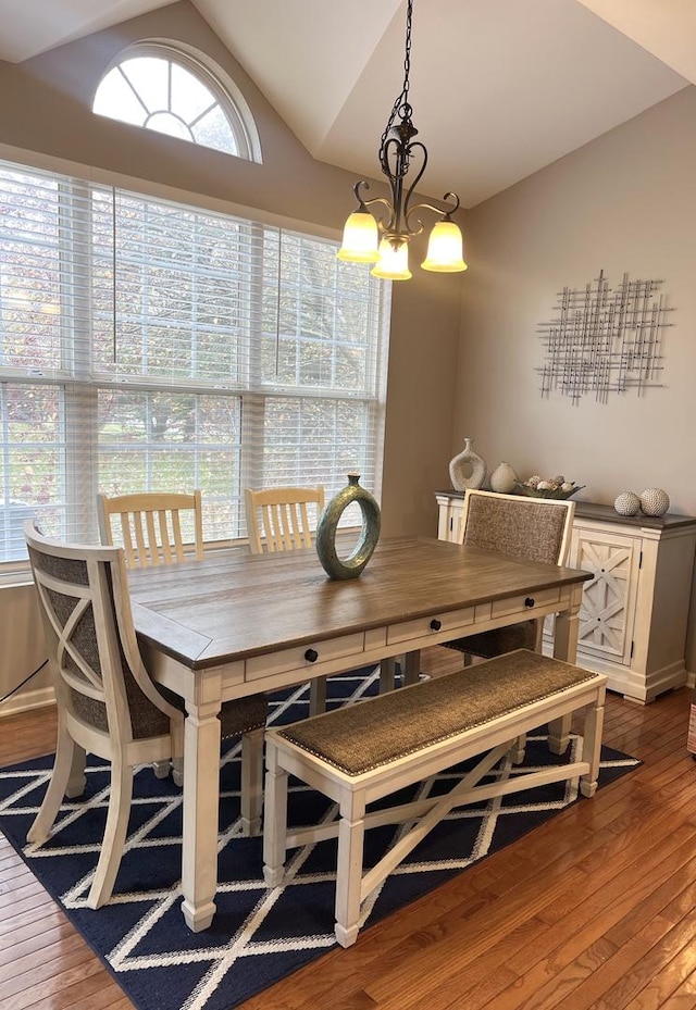 dining space with lofted ceiling, hardwood / wood-style floors, and an inviting chandelier