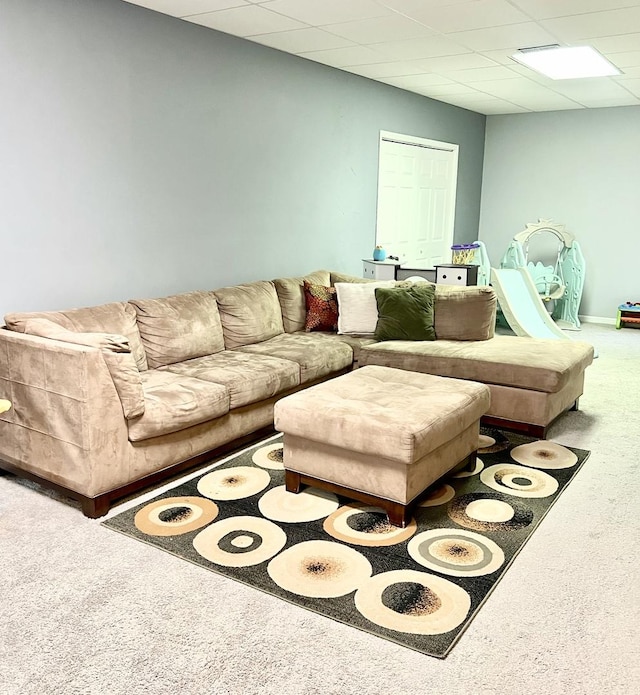 living room featuring carpet floors and a drop ceiling