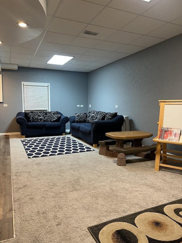 living room featuring a drop ceiling and carpet