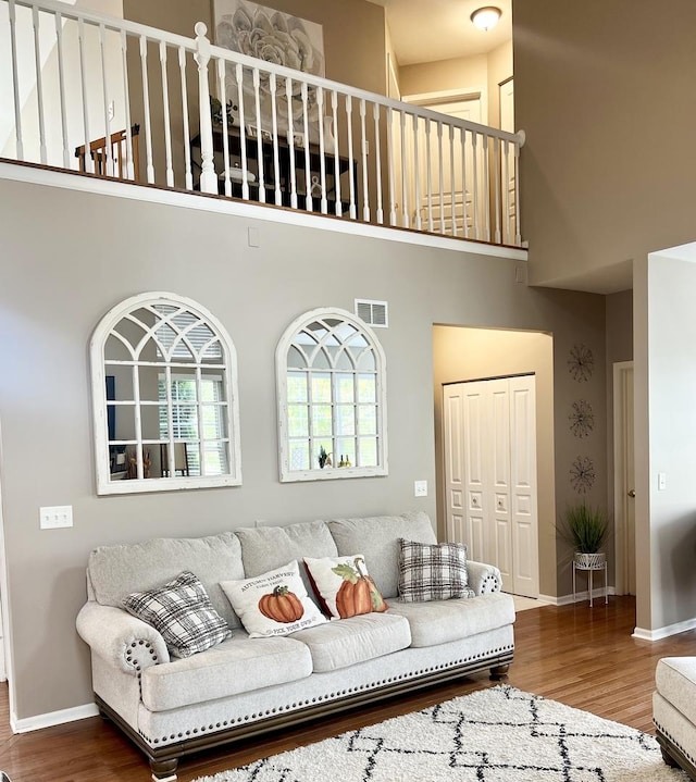 living room with wood-type flooring and a towering ceiling