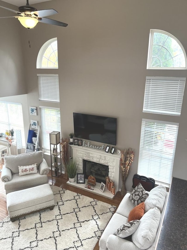 living room featuring a high ceiling, ceiling fan, hardwood / wood-style floors, and a fireplace