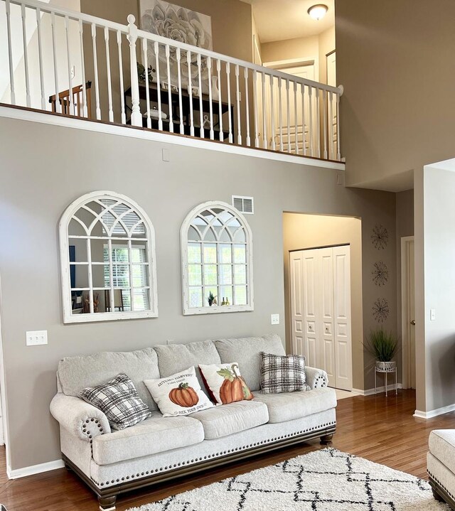 living room with wood-type flooring, a fireplace, and a high ceiling