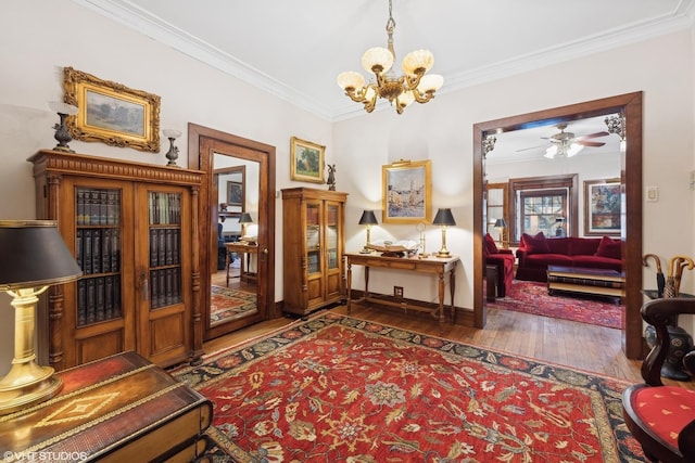 sitting room featuring dark wood-type flooring, ornamental molding, and ceiling fan with notable chandelier