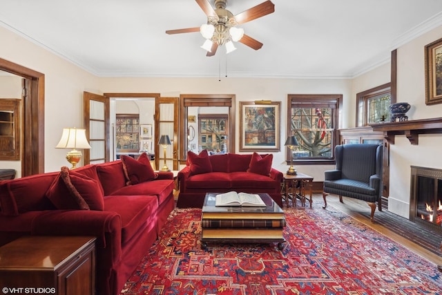 living room with wood-type flooring, ornamental molding, and ceiling fan