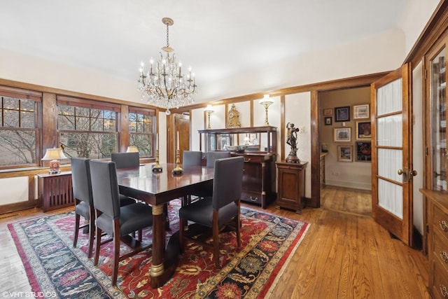 dining area featuring a notable chandelier, light hardwood / wood-style floors, and french doors