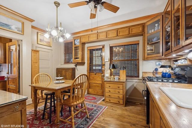 dining area with crown molding, ceiling fan with notable chandelier, and light hardwood / wood-style flooring