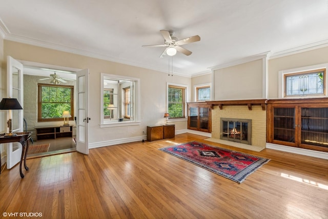 living room featuring crown molding, wood-type flooring, ceiling fan, and a fireplace