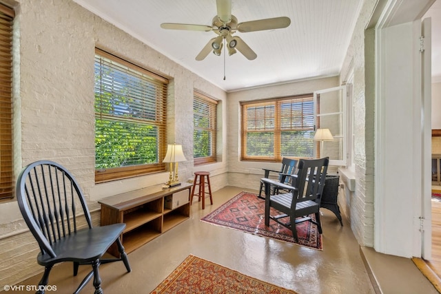 sitting room with concrete flooring, crown molding, plenty of natural light, and ceiling fan