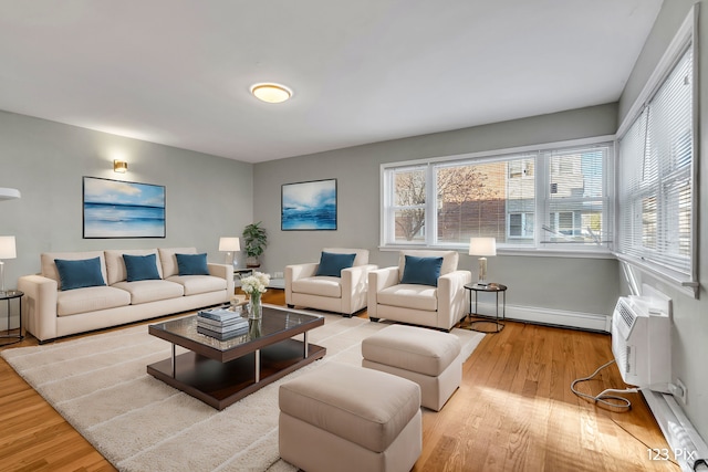 living room featuring baseboard heating, light hardwood / wood-style floors, and a wall mounted air conditioner