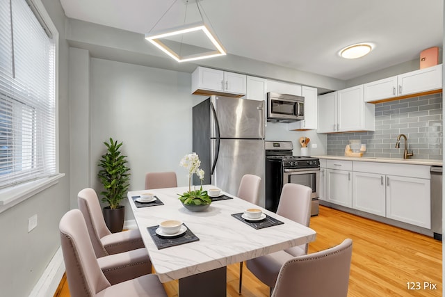 kitchen with decorative backsplash, white cabinetry, light hardwood / wood-style floors, and appliances with stainless steel finishes