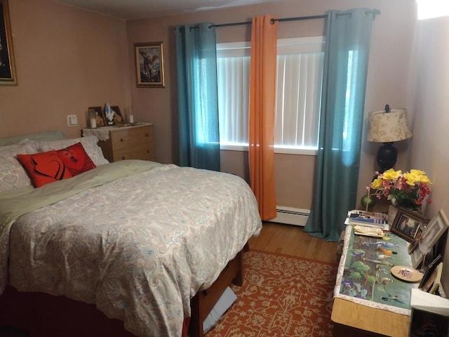 bedroom featuring baseboard heating and hardwood / wood-style floors