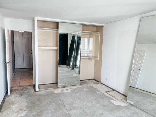 unfurnished bedroom with concrete flooring and a closet