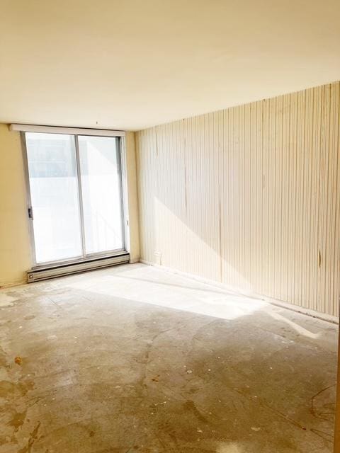 empty room featuring concrete flooring and a baseboard heating unit