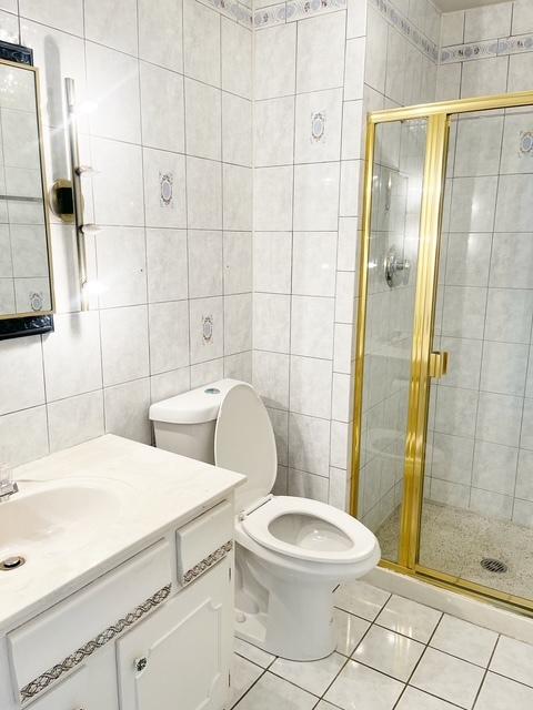 bathroom with vanity, a shower with shower door, and tile walls