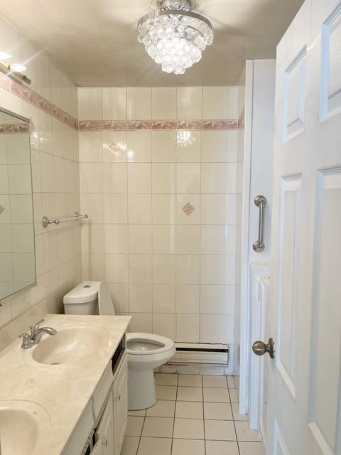 bathroom featuring tile walls, vanity, a baseboard heating unit, toilet, and tile patterned floors