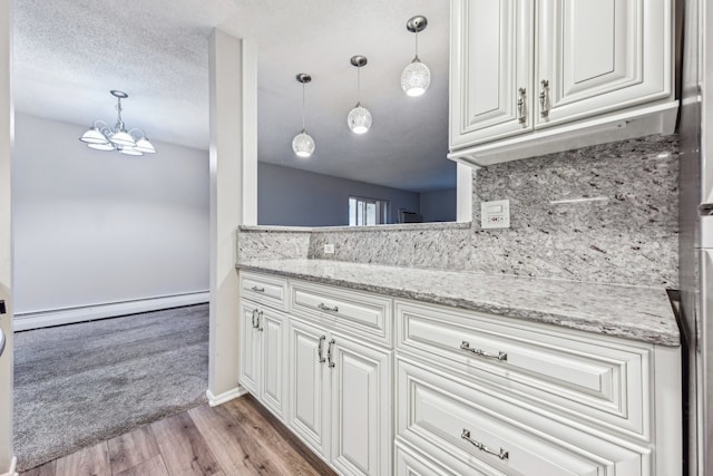 kitchen with pendant lighting, white cabinetry, light hardwood / wood-style flooring, and a baseboard radiator