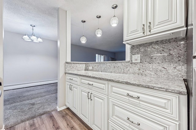 kitchen featuring white cabinetry, a baseboard heating unit, decorative light fixtures, and a textured ceiling