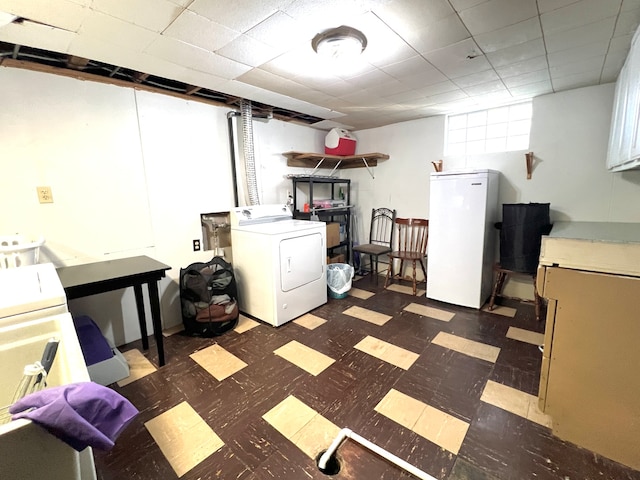 basement with independent washer and dryer, a paneled ceiling, and fridge