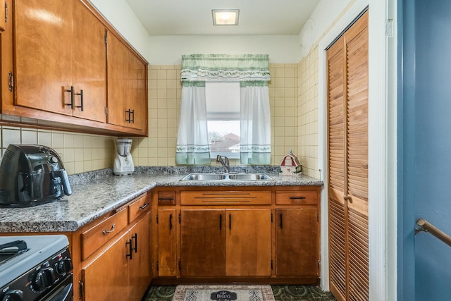 kitchen featuring sink, black range with gas stovetop, and backsplash