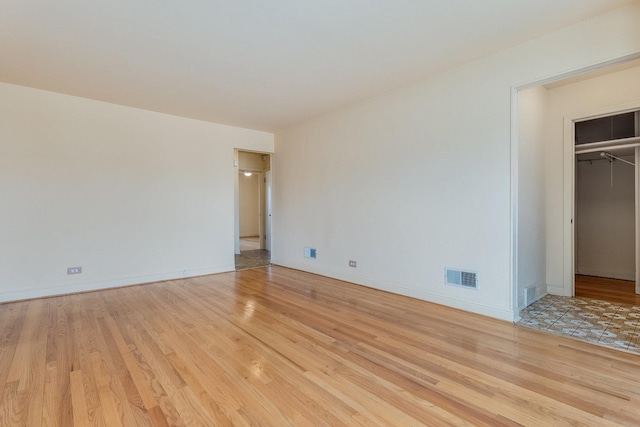 unfurnished bedroom featuring a walk in closet and light hardwood / wood-style floors