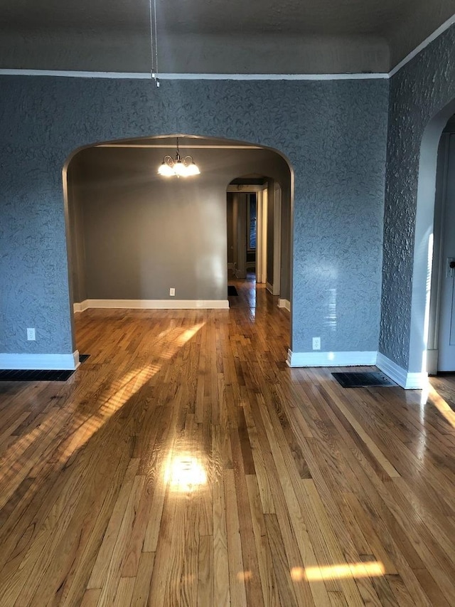 unfurnished dining area featuring crown molding, an inviting chandelier, and hardwood / wood-style flooring