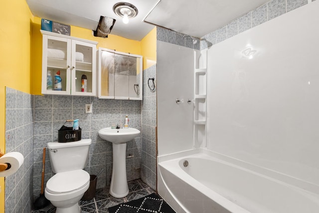 bathroom featuring shower / bathing tub combination, toilet, and tile walls