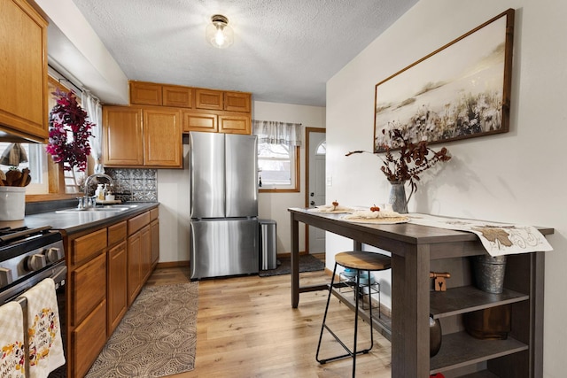 kitchen featuring a textured ceiling, light hardwood / wood-style floors, sink, and stainless steel appliances