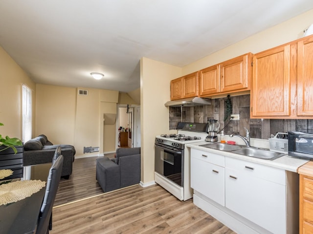 kitchen with backsplash, white gas stove, light wood-type flooring, and sink