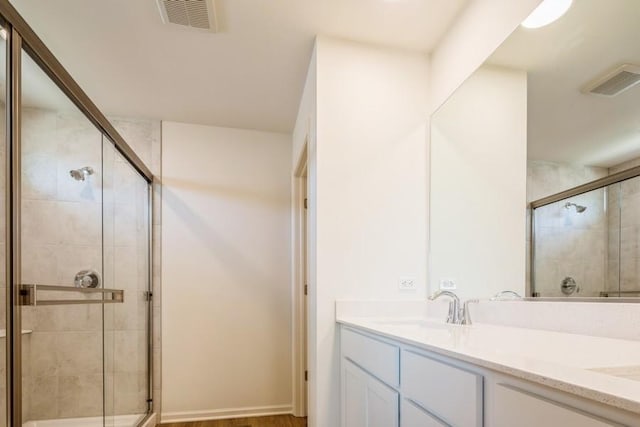 bathroom featuring hardwood / wood-style floors, vanity, and a shower with shower door