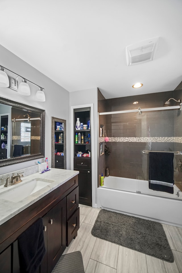 bathroom featuring combined bath / shower with glass door, built in shelves, and vanity