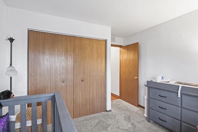 bedroom with a crib, light colored carpet, and a closet