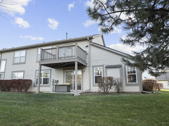 rear view of property with a yard and a balcony